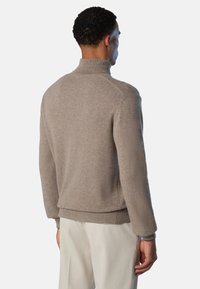Maglione beige lavorato a maglia con collo alto, polsini e orlo a coste. Tessuto morbido, vestibilità comoda e design minimalista.