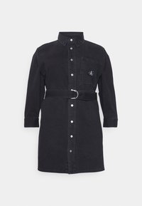 Musta denim-mekko pitkillä hihoilla, nappikiinnitys edessä ja yhteensopiva vyö, jossa on pyöreä solki. Mukana rintatasku logolla.