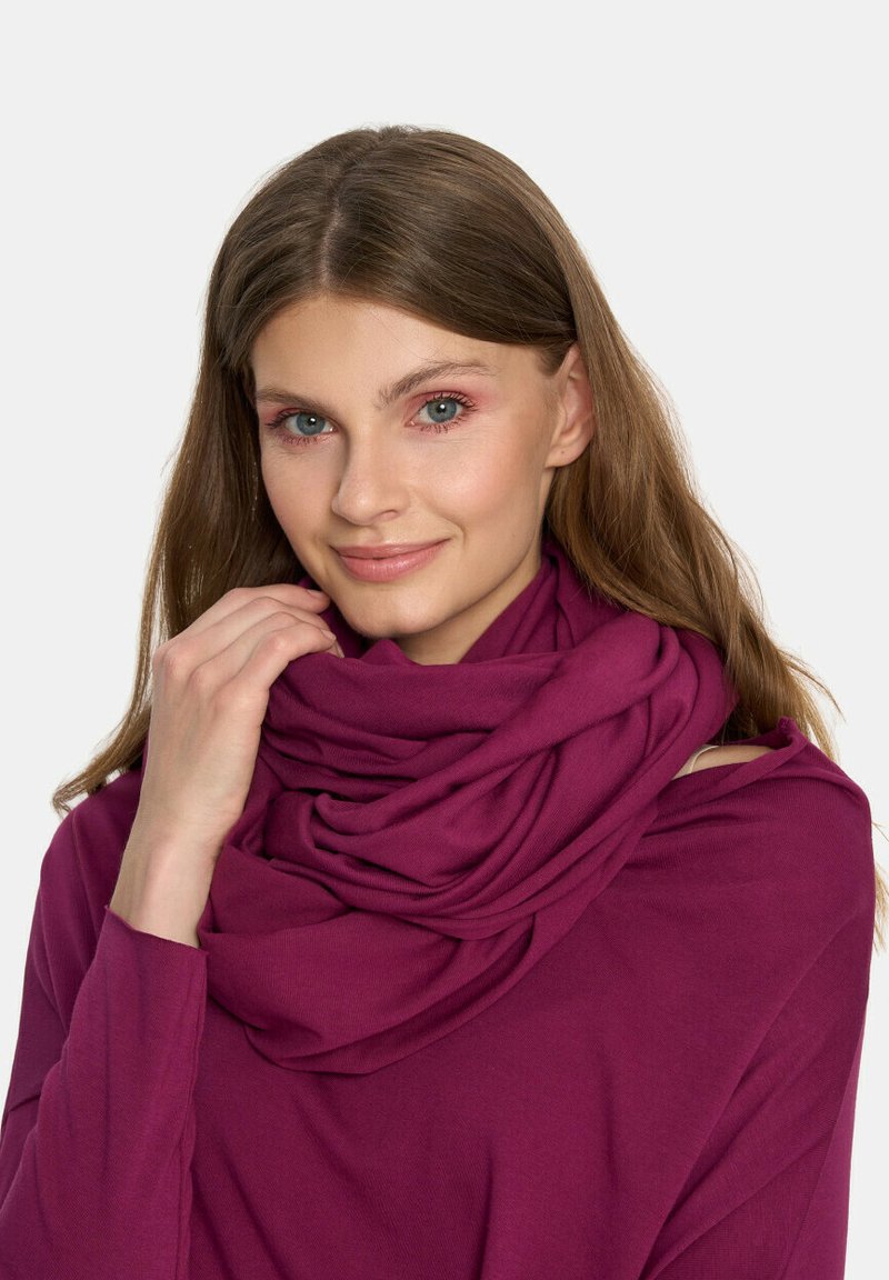 Fioletowy szalik w formie swetra na szyi, charakteryzujący się miękką, gładką fakturą oraz prostym, zaokrąglonym kształtem bez widocznych wzorów.