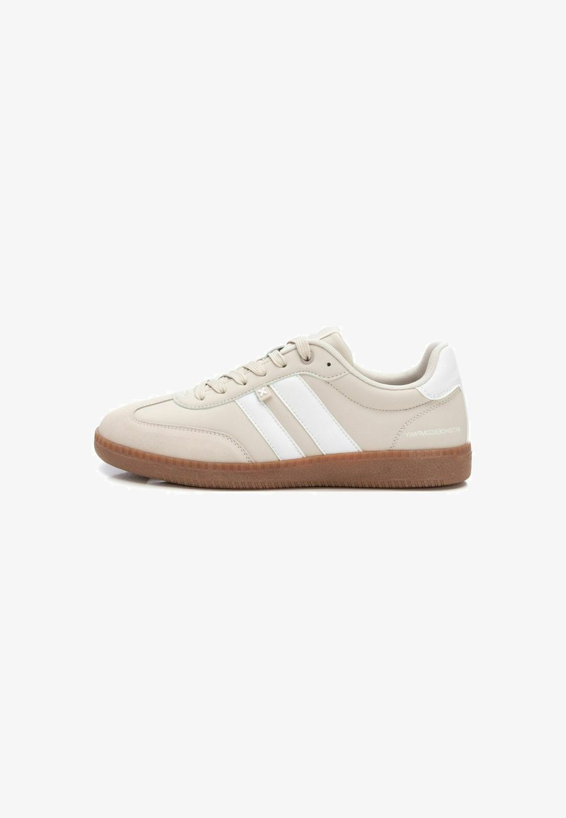 Zapatillas beige con rayas blancas, material sintético suave, punta redonda y suela de goma con un patrón texturizado.