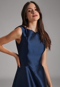 Navy-blaues Satinkleid mit Rundhalsausschnitt, ärmellosem Design und strukturiertem Oberteil. Mit schmeichelnden Nähten und einem fließenden Rock.
