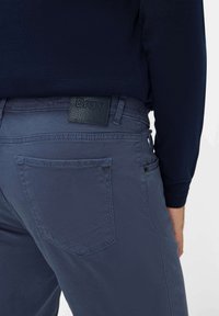 Pantalon bleu marine avec une finition texturée, doté d'un patch logo Brax noir et de poches renforcées à l'arrière.