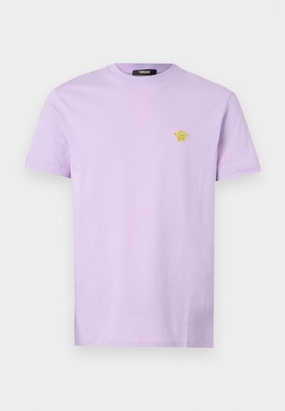 Tricou din bumbac de culoare violet deschis, cu un mic logo galben Versace pe partea stângă a pieptului. Mâneci scurte și guler clasic de tip crew.