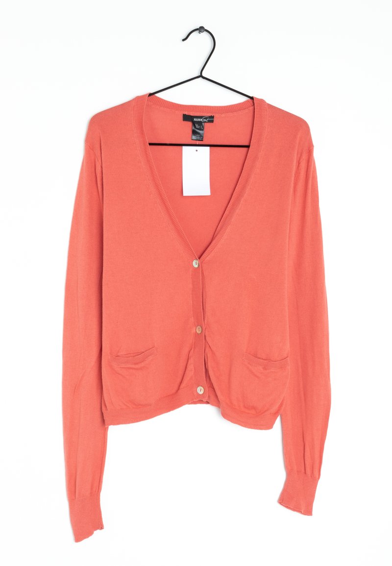 Cardigan corail avec un décolleté en V, trois boutons, deux poches avant et des poignets côtelés. Fabriqué en tissu tricoté doux. Accroché à un crochet noir.