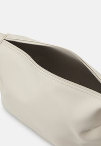 Borsa in pelle morbida di colore crema, con una texture liscia, chiusura a zip e un ampio interno con foderatura scura. Design minimalista.