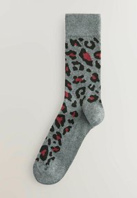 Pelēkās zeķes ar leopardu rakstu melnā un sarkanā krāsā, ar ribotu piedurknīti un gludu tekstūru.