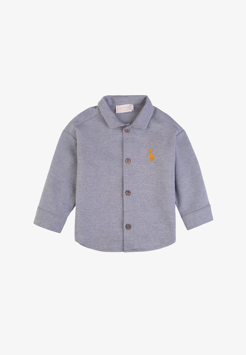 Camicetta grigia a maniche lunghe con colletto abbottonato, quattro bottoni marroni e una grafica arancione sul petto. Tessuto testurizzato con una leggera lucentezza.