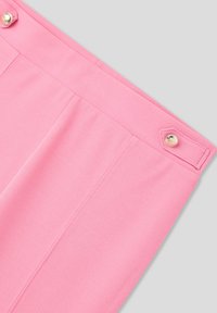 Pantaloni tailored rosa con due tasche frontali, una texture di tessuto liscia e un accento in bottone d'oro sulla vita.