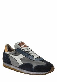 Scarpa sportiva con un mix di materiali blu navy, grigio e bianco, caratterizzata da una tomaia testurizzata, chiusura con lacci e una suola in gomma con un motivo.