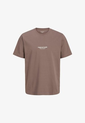 Lühikeste varrukatega, ümmarguse kaelusega T-särk pruuni puuvillast. Esiküljel on keskel valge tekst "Original Studio". Klassikaline, mugav lõige.