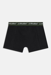 Sorte boksershorts laget av myk stoff med grønn midje som har hvit "JJ Studios" merkevare. Inkluderer sømdetaljer.
