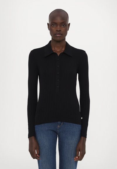 Polo de manga larga negro de canalé con cuello puntiagudo, cierre de botones y un ajuste ceñido. La textura es notablemente suave, con un ligero estiramiento.