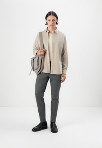 Camisa de botón color beige claro, pantalones grises, zapatos negros y un bolso cruzado gris. Textura suave con un diseño minimalista y sin patrones.