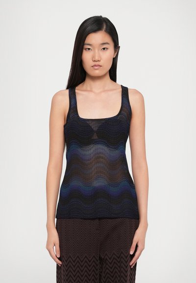 Zwarte en marineblauwe geribbelde gebreide tanktop met een golvend patroon en vierkante halslijn, gecombineerd met gemusterde bruine wijde broek.