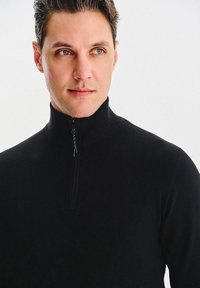 Czarny sweter na zamek z wysokim kołnierzem. Wykonany z miękkiego materiału, posiada pół-zamek i dopasowany fason.