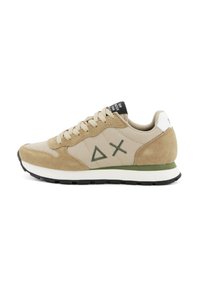Beige und braune Wildleder-Sneaker mit grünen Dreiecken und Kreuz-Logos an der Seite, weißer Zwischensohle, schwarzer Laufsohle und beigen Schnürsenkeln.