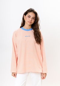 Langarmgestreiftes Hemd in sanftem Orange und Weiß mit blauem Kragen. Verziert mit gesticktem Logo auf der Brust. Aus Baumwollmischung, lässige Passform.