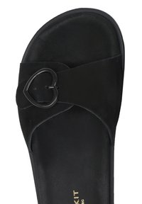 Zwarte suede sandaal met een hartvormige zwarte metalen gesp, zachte textuur en open design. De zool is plat en glad met minimale accenten.