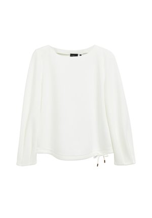 Blouse blanche à manches longues avec encolure ronde et petit détail de lien noué au bas de l'ourlet sur fond uni.