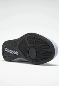 Black rubber outsole with textured grip patterns, featuring a white Reebok logo. Designed for durability and traction in various conditions.