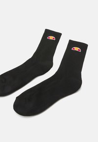 Schwarze Baumwollsocken mit gerippter Struktur, ausgestattet mit einem kleinen, mehrfarbigen Logo am Bündchen. Standard Crew-Länge, glatte Verarbeitung und keine sichtbare Naht.
