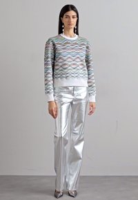 Πουλόβερ με πολύχρωμο κυματιστό μοτίβο, στρογγυλή λαιμόκοψη και λευκή λεπτομέρεια; συνδυασμένο με γυαλιστερά ασημί κολάν και μυτερά ασημί παπούτσια.