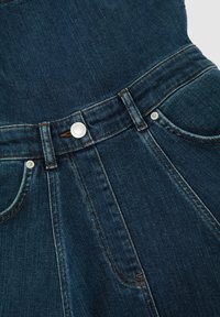 Ciemnoniebieska spódnica dżinsowa z przodu na guziki, szlufkami na pasek oraz widocznym przeszyciem na kieszeniach i szwach.