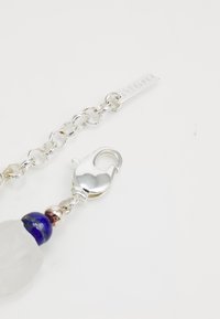 Pulsera de cadena de plata con un cierre de langosta, una cuenta de cristal claro y una cuenta decorativa azul con acentos metálicos.