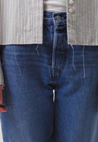 Lett gulstripe skjorte over en hvit tank topp, sammen med høyt liv mørk denim jeans med avslappet passform og flisete kanter.