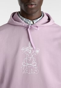 Sudadera morada clara con cordón, que presenta un gráfico blanco de un conejo de dibujo animado y un logotipo. La tela parece suave y similar al algodón.