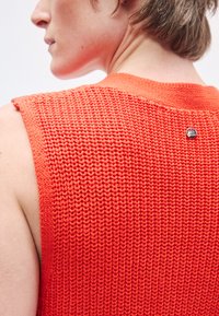 Αμάνικη πλεκτή μπλούζα σε φωτεινό πορτοκαλί με υφή στο σχέδιο και ριμπ λαιμόκοψη. Διαθέτει μικρή ασημένια ετικέτα στο πίσω μέρος.