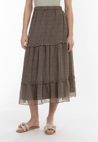 Brun, lagdelt maxi-nederdel lavet af letvægtigt stof med blomstermønster. Har en smocked talje og en luftig silhuet.