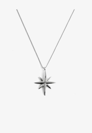 Collier pendentif en forme d'étoile argentée aux pointes aiguës, suspendu à une chaîne délicate, avec une finition métallique polie et une texture lisse.