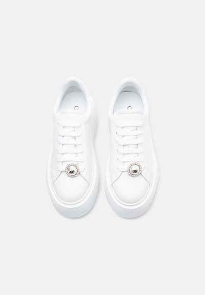 Άσπρα αθλητικά παπούτσια από λείο δέρμα, με στρογγυλή διακοσμητική λεπτομέρεια με κρύσταλλο γύρω από τα κορδόνια και χοντρή σόλα από καουτσούκ.