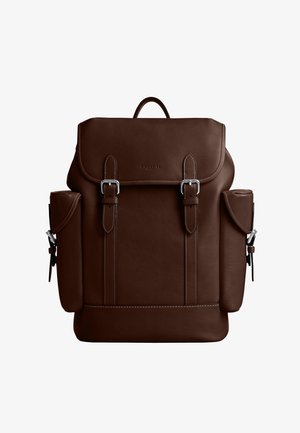 Sac à dos en cuir marron foncé avec deux sangles à boucle à l'avant, poches latérales à rabats et une poignée supérieure.