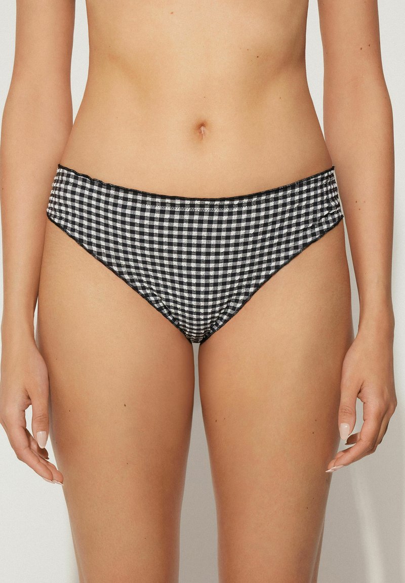 Bikini kalhotky v černobílé kostkované vzoru s hladkým textilním povrchem, vysokým vykrojením nohavic a elastickým pasem.