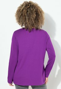 Maglietta a maniche lunghe viola con colletto rotondo, texture liscia e vestibilità comoda, vista dalla schiena, con orlo dritto e senza dettagli visibili.