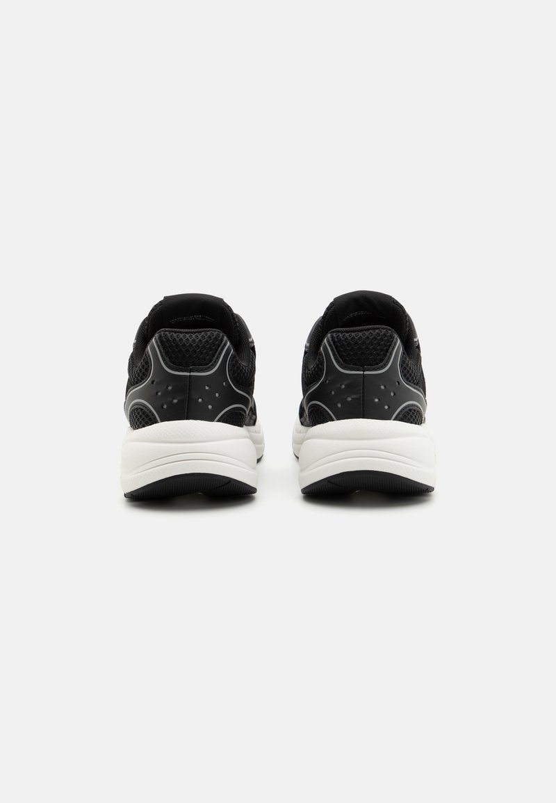 Baskets de sport noires avec une tige en mesh, un col rembourré et une semelle extérieure blanche contrastante. Présente des accents texturés et un design moulé.