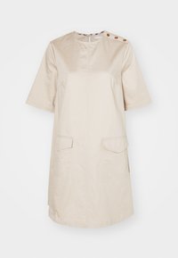 Vestido de algodão bege com mangas curtas, decote redondo, dois bolsos frontais e botões decorativos no ombro. Linha de bainha reta.