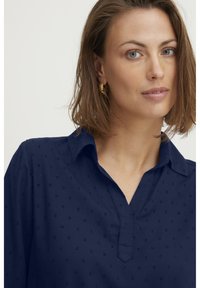 Camicia blu navy con colletto e un motivo testurizzato discreto. Presenta una patta e un tessuto leggero. Design elegante e su misura.