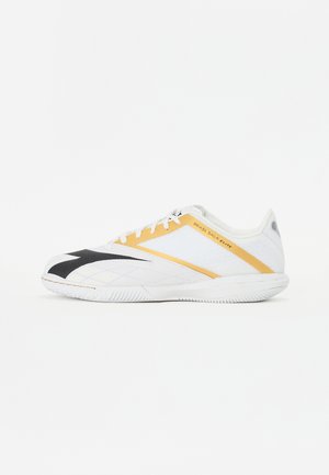 White athletic shoe with black and yellow accents, a textured surface, and a low profile design. Features laces and a supportive heel.