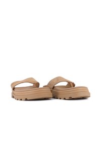 Bruna flip-flop sandaler har ett mjukt mockaband, vadderad innersula och en texturerad gummiyttersula med ett mönstrat grepp.