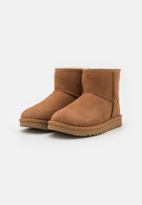 Stivali ankle in suede marrone con una morbida fodera interna, punte rotonde, dettagli cuciti e suola in gomma texturizzata.