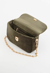 Oliwkowa zamszowa torba z klapką, złotą okuciem i łańcuszkowym paskiem. Wewnętrzna kieszeń z zamkiem błyskawicznym zapewnia bezpieczne przechowywanie.