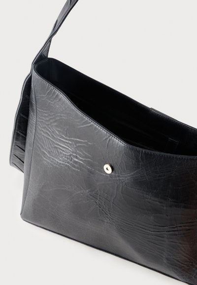 Μαύρη τσάντα ώμου από δερματίνη με υφή, με κλείσιμο με μαγνητικό πατητό κουμπί, ανοιχτό πάνω μέρος που αποκαλύπτει την εσωτερική επένδυση και θήκη με φερμουάρ στο εσωτερικό.