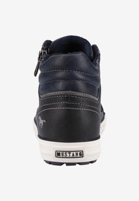 Bottines montantes en cuir noir avec accents gris clair, semelle blanche et détail de fermeture éclair sur le côté. Caractéristiques : tige texturée et logo sur le talon.