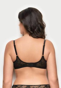 Sort blond lace bralette med justerbare stropper, blomster mønster og en hægte- og øje lukning på bagsiden, der har blødt, gennemsigtigt stof.