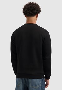 Zwart sweatshirt met ronde hals en ribgebreide manchetten, met een zachte textuur en casual pasvorm, gecombineerd met lichtblauwe jeans.