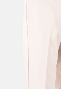 Pantaloni rosa chiaro con una texture liscia, caratterizzati da gambe dritte e cuciture sottili per un aspetto sartoriale.