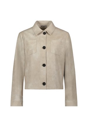 Beige perforierte Lederjacke mit Kragen, Knopfverschluss, zwei Brusttaschen und langen Ärmeln. Schwarze Knöpfe bilden einen Kontrast zum Stoff.
